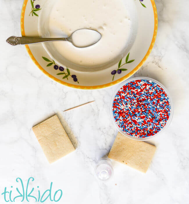 Materials for decorating sugar cookies by dipping cookies in royal icing.