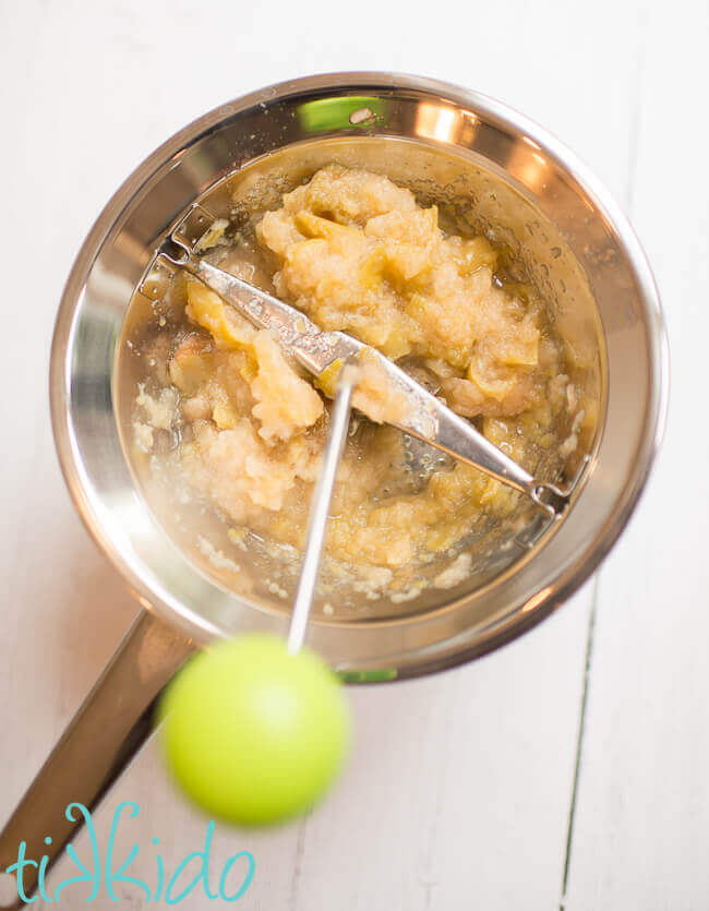 Cooked apples in a food mill to make homemade applesauce.