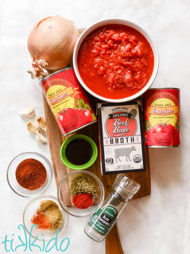 Ingredients for Instant Pot chili on a wooden cutting board on a white marble background.