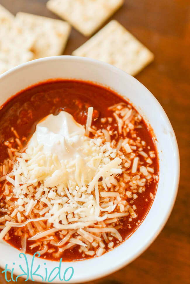 Instant pot no bean chili in a white bowl topped with sour cream and shredded cheese