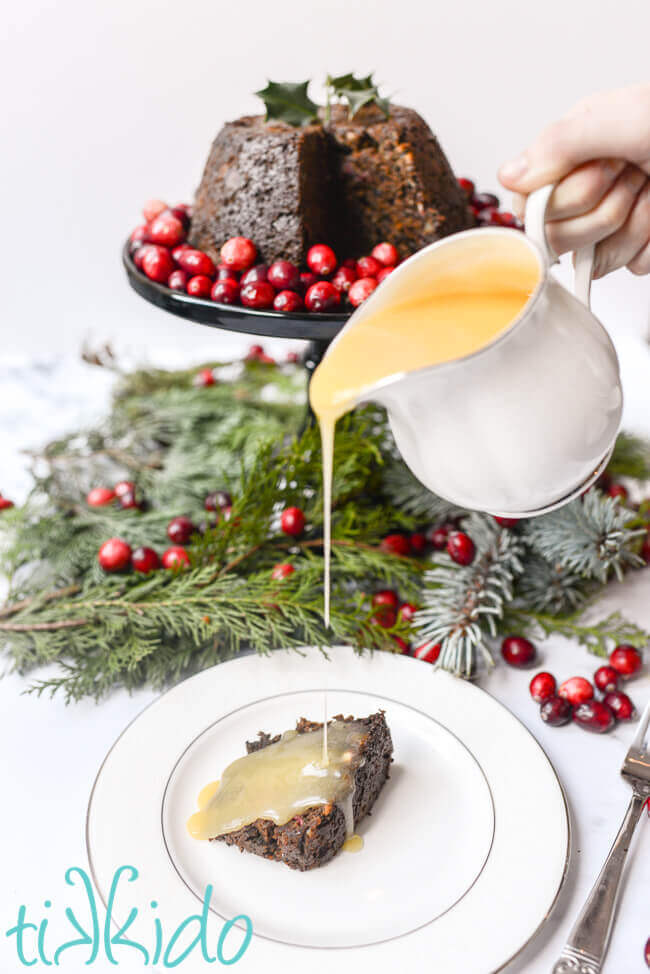 Hard sauce being poured over a slice of Christmas pudding.