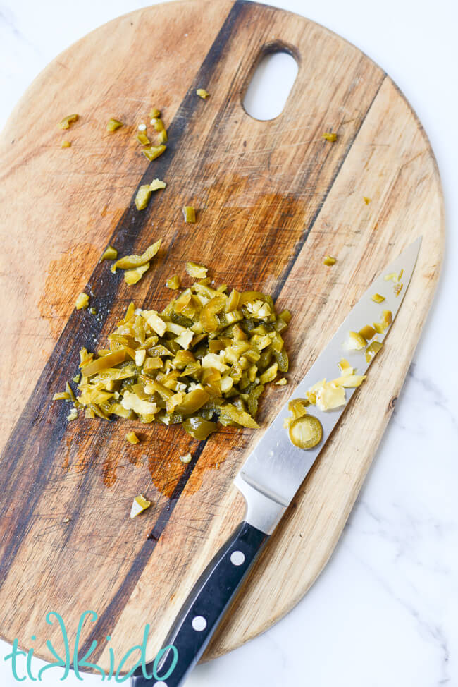 Jalapeños being chopped on a wooden chopping board, for making Jalapeño Cheddar Bagels.