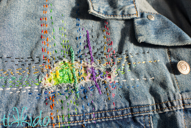 Hole in jean jacket patched using easy Sashiko mending techniques.