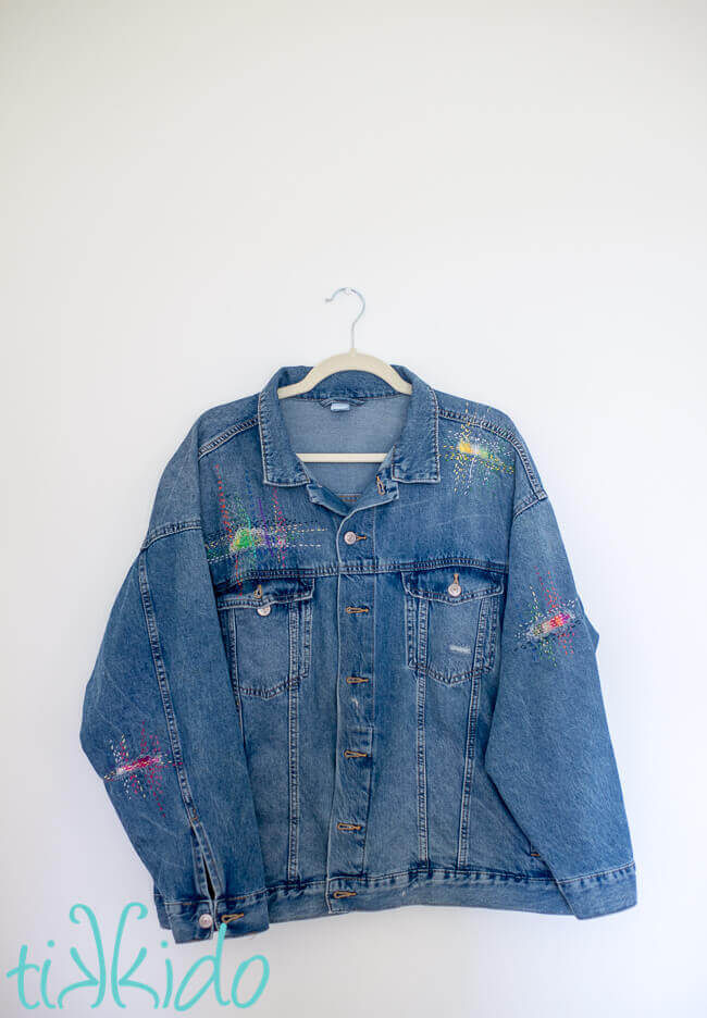 Jean jacket with holes patched with sashiko mending, creating beautiful visible mending embellishments.