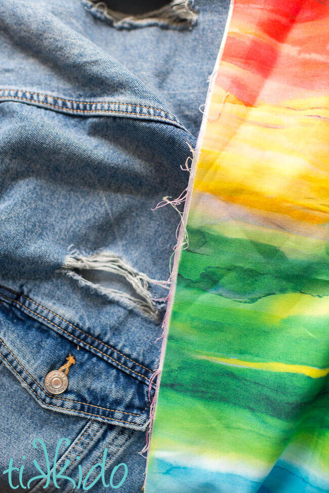 Rainbow watercolor fabric used for sashiko visible mending of a jean jacket.
