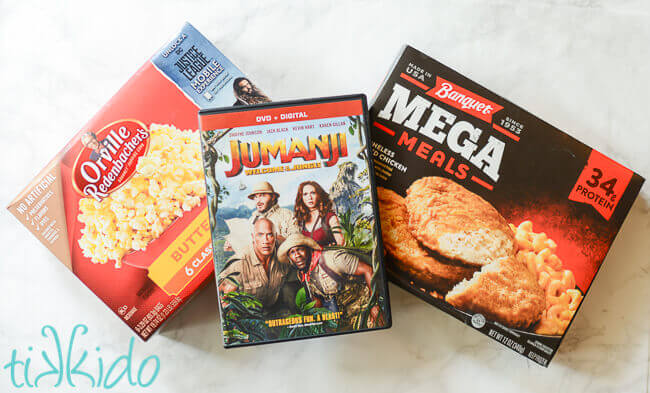 Microwave popcorn box, jumanji dvd, and microwave dinner on white marble background