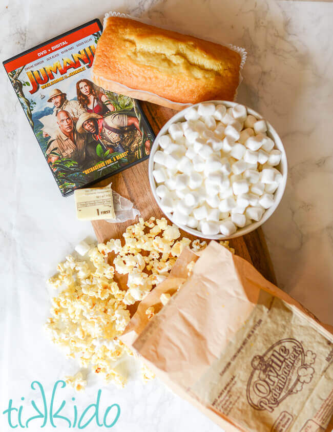Ingredients for pound cake popcorn treat bars on wooden cutting board with Jumanji movie.