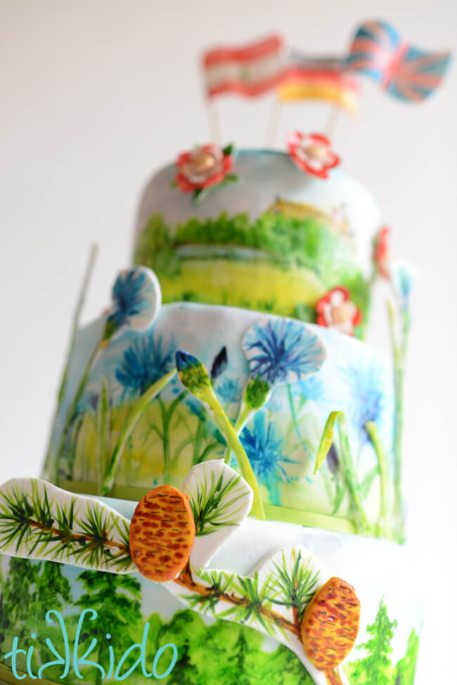Three tier cake covered in fondant, decorated with painted details.