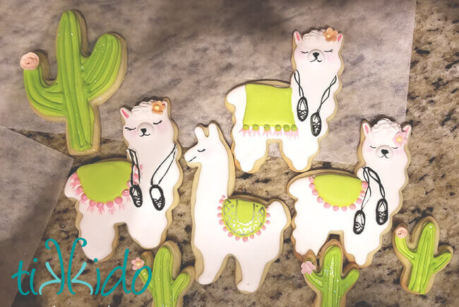 Irish dancing llama cookies and cactus cookies on a granite surface.