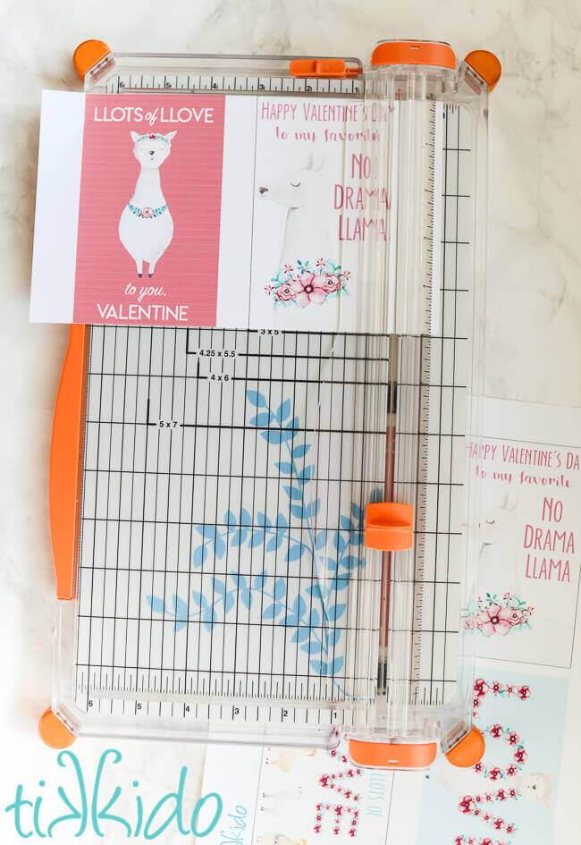 Free printable llama themed valentines for Valentine's Day being cut out with a paper cutting tool.
