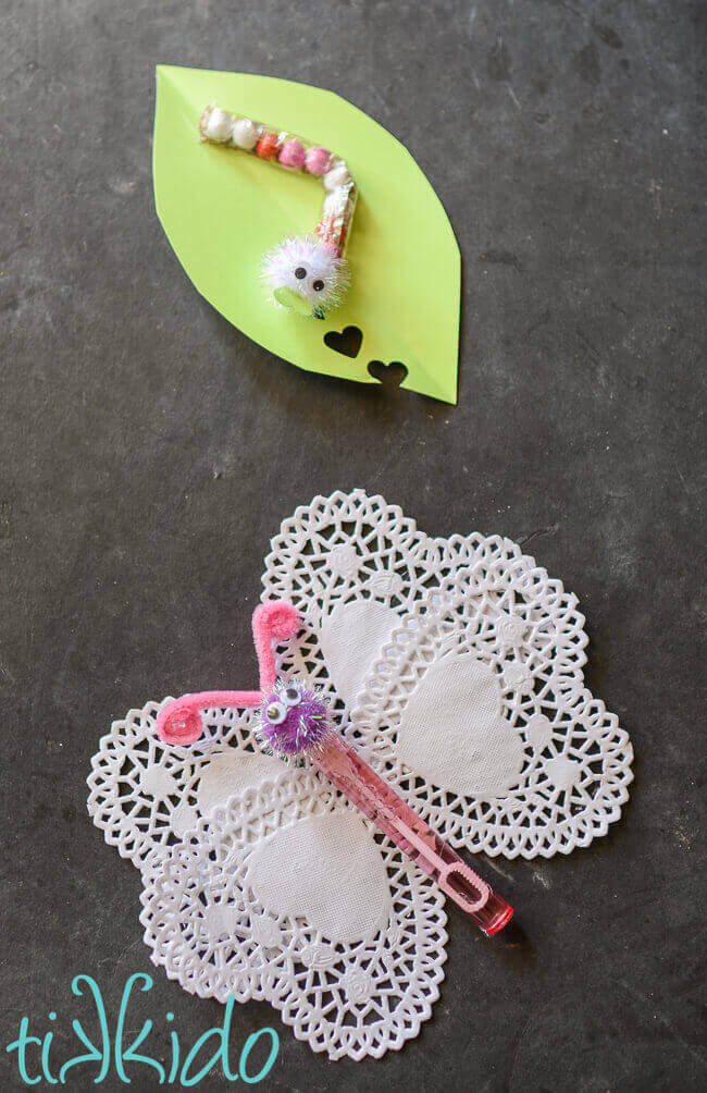 Chocolate caterpillar on leaf valentine and butterfly bubbles valentine on black chalkboard background.