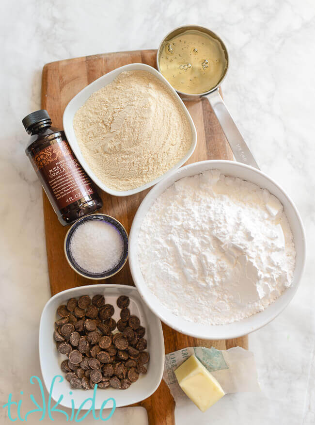 Ingredients for chocolate malt tootsie roll candies on a wooden cutting board on a white marble background