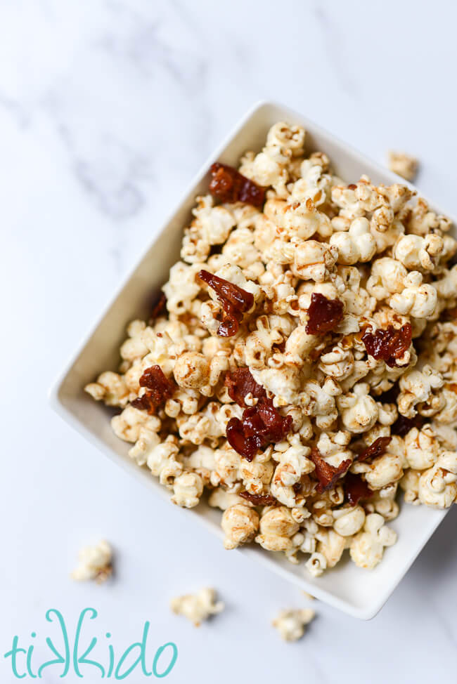 Maple Bacon Popcorn in a white, square bowl, on a white marble surface.