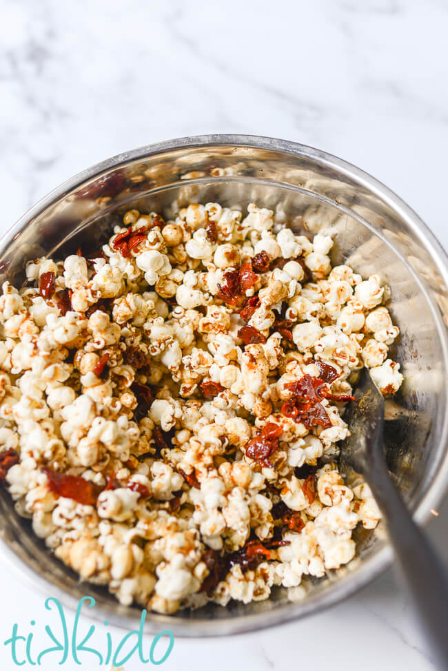 Maple Bacon Popcorn being tossed to evenly coat the popcorn with the browned butter, maple syrup, and bacon mixture.