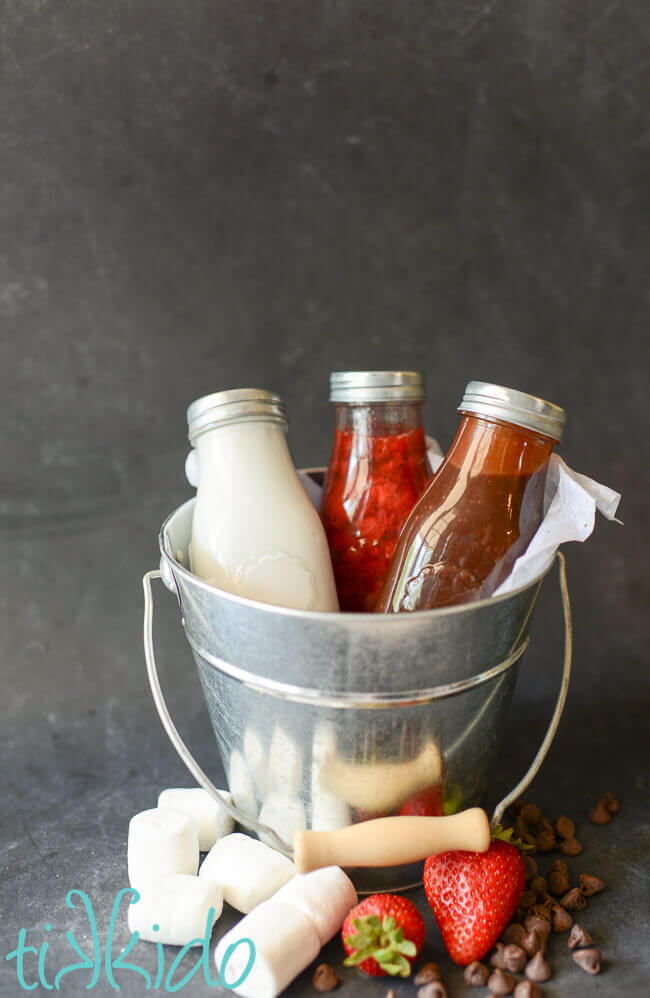 Marshmallow sauce, strawberry sauce, and chocolate fudge sauce in a silver bucket.