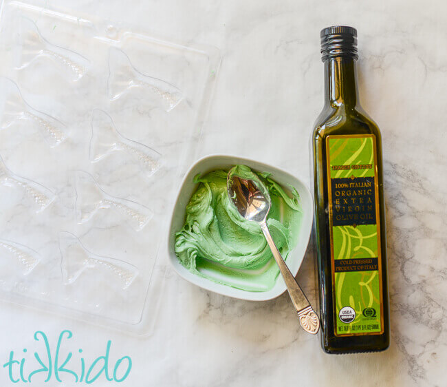 Thick green chocolate melts next to a bottle of olive oil.