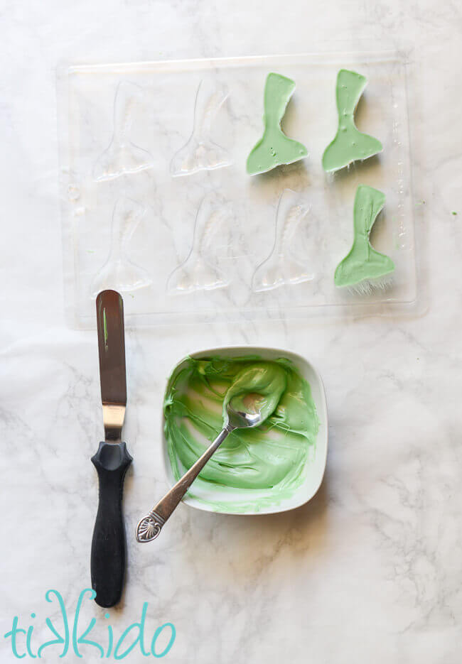 Green chocolate melts being put into mermaid tail chocolate mold.