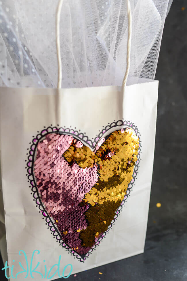 white gift bag with pink and gold mermaid fabric heart on a black chalkboard background.
