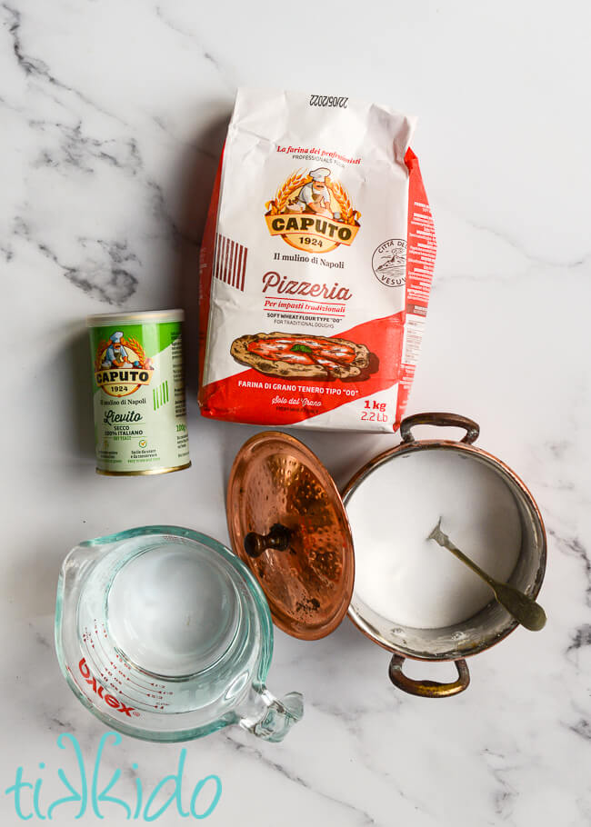 Neapolitan Pizza Dough Recipe ingredients on a white marble surface.