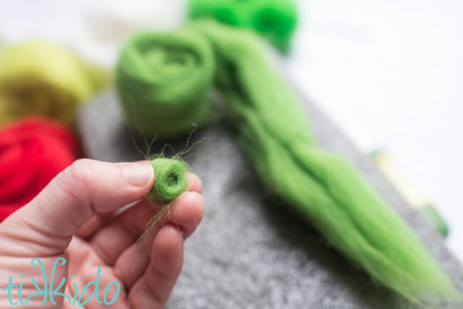 Green wool roving rolled into a ball shape to make a felt ball.
