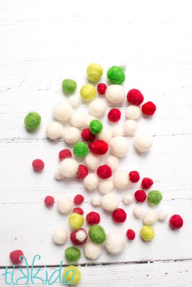 Felt balls made with needle felting on a white wooden background.