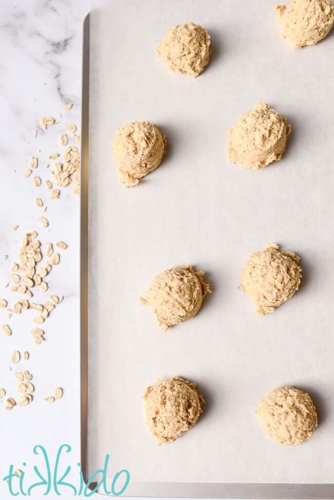 Oatmeal cookie dough scooped on a parchment lined cookie sheet to make chewy oatmeal cookies.