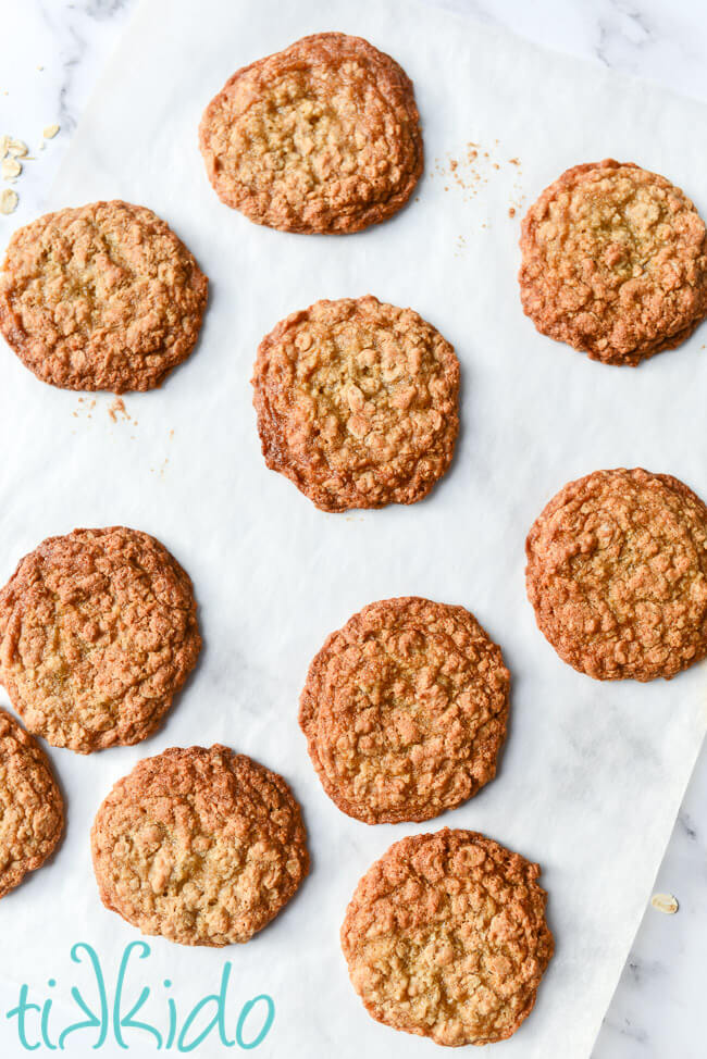 Freshly baked chewy oatmeal cookies on a sheet of parchment paper.