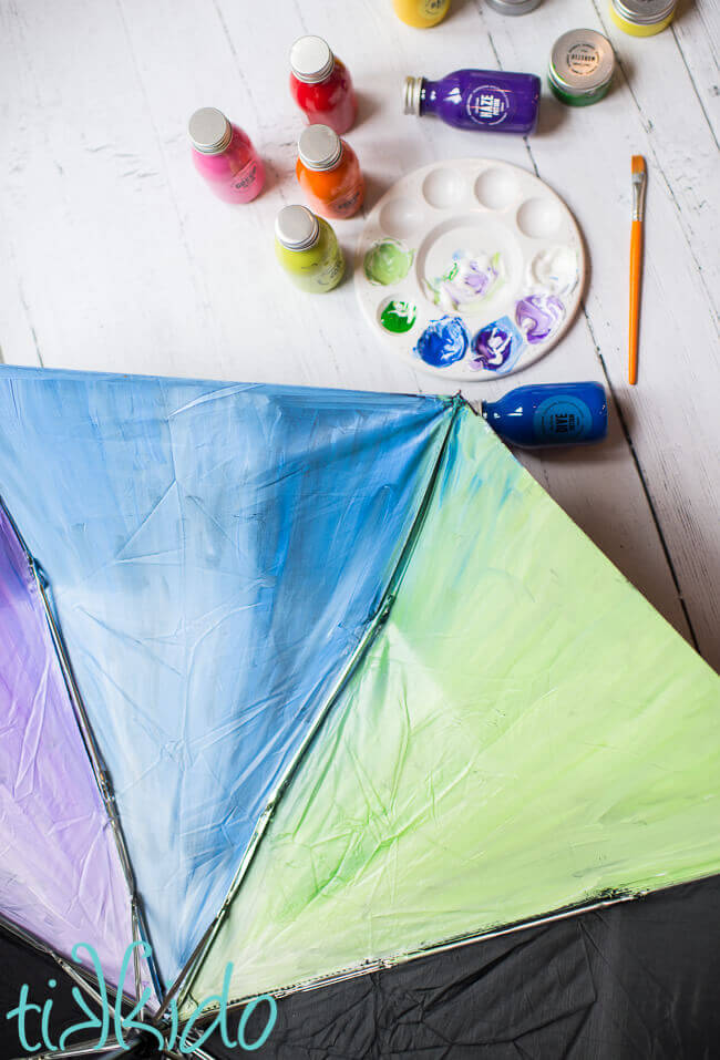 Black umbrella being painted with acrylic paint.