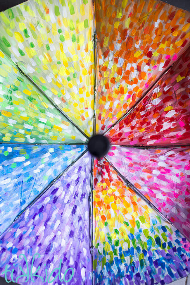 Painted umbrella painted with acrylic paint in an abstract rainbow pattern.