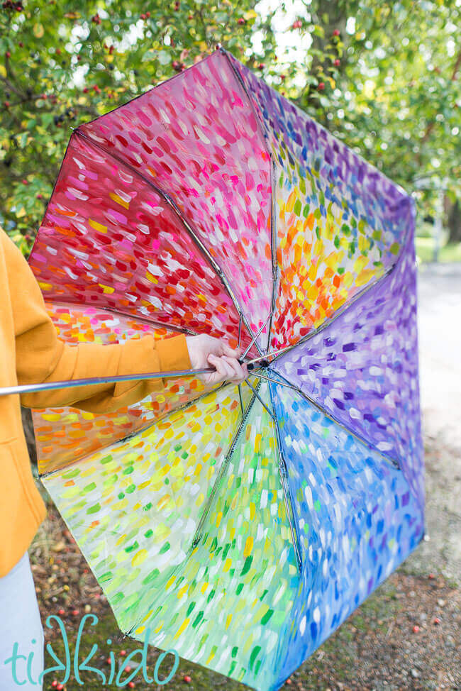 DIY painted umbrella painted in abstract rainbow colors with acrylic paint.