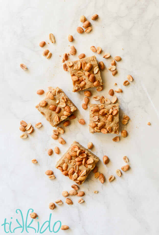 Peanut butter bar cookies on a white marble background surrounded by peanuts.