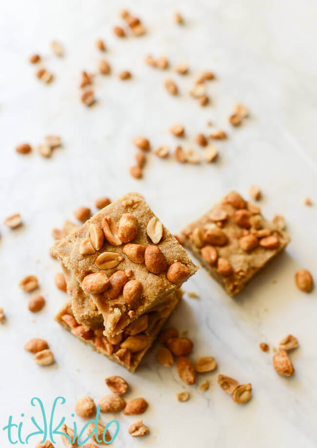 Peanut butter bar cookies on a white marble background surrounded by peanuts.