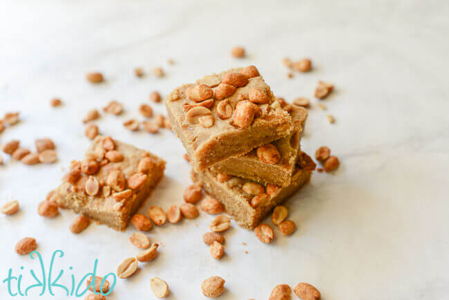 Peanut butter bar cookies on a white marble background surrounded by peanuts.