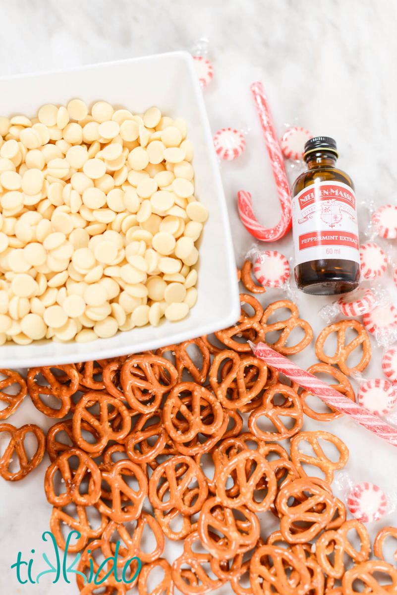 Ingredients for peppermint white chocolate covered pretzels on a white marble surface.