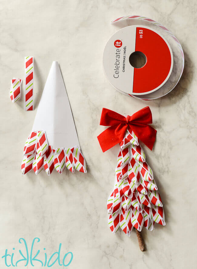 Loops of red and white striped ribbon being glued on a cardstock triangle to make the Ribbon Tree Gift Tag