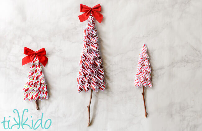 Three Ribbon Tree Gift Tags made with red and white striped ribbon on a white marble background.