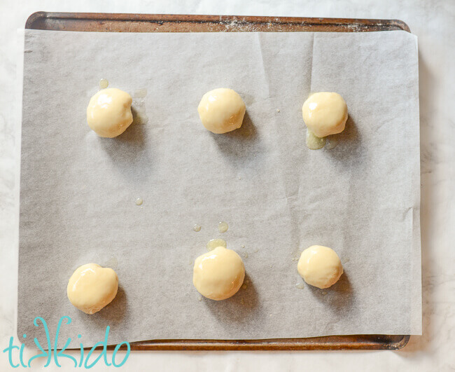 Balls of kolache dough on a parchment lined cookie sheet.