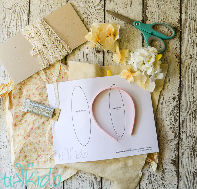 Materials for bunny ear headband, including fabric, wire, printable bunny ear templates, a pink headband, artificial flowers, and scissors.