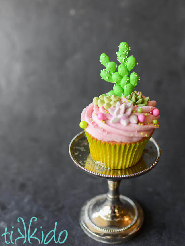 prickly pear cupcake topped with pink prickly pear icing, sprinkles, and royal icing cactus and succulents.