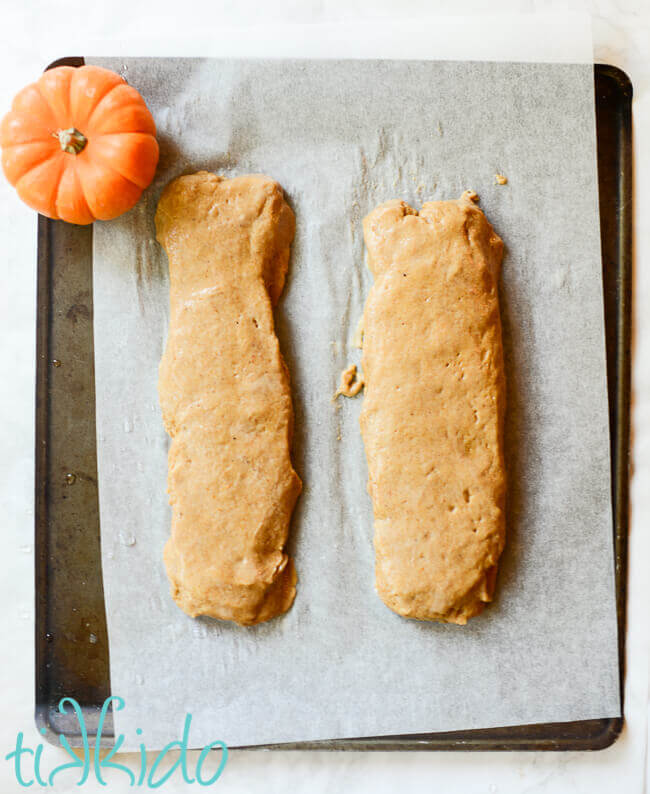 Pumpkin biscotti dough shaped into two logs on a baking sheet.