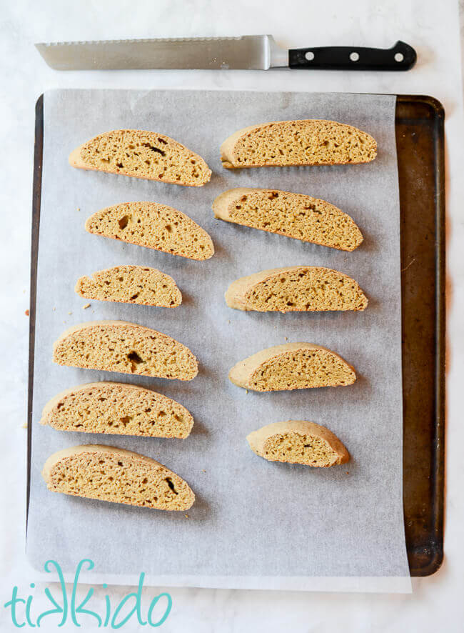 Sliced pumpkin biscotti arranged on a parchment lined cookie sheet ready for a second bake.