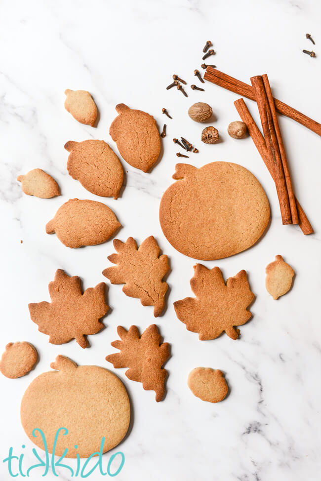 Pumpkin Spice Sugar Cookies and whole pumpkin pie spices on a white marble surface.