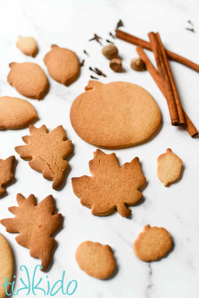 Pumpkin Spice cut out Sugar Cookies and whole spices on a white marble surface.