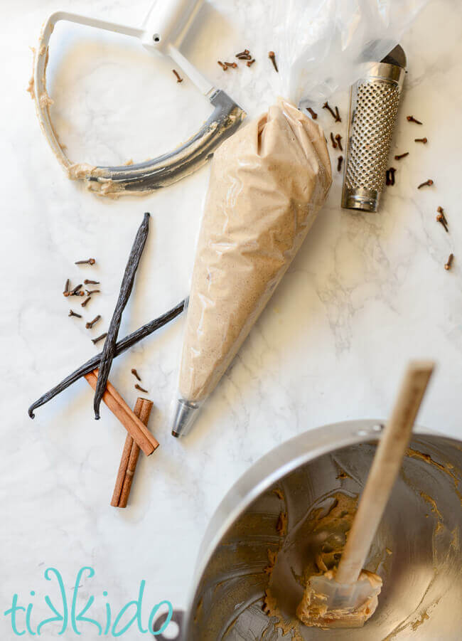 Pumpkin Spice Vanilla Wafer Cookies batter in a piping bag, surrounded by a mixing bowl and whole spices.