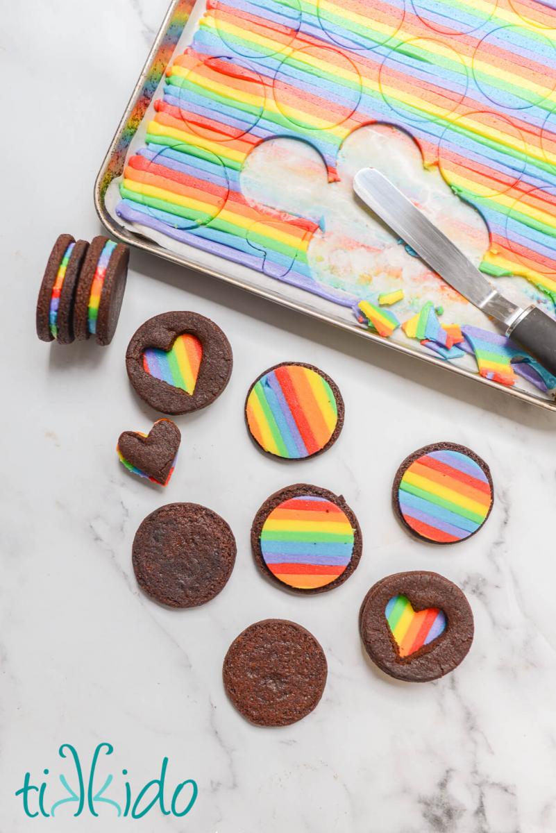 Rainbow Oreos being assembled.  Some of the rainbow oreos have a heart shaped cutout in the top cookie so you can see the rainbow from the top as well as the edges of the cookie.