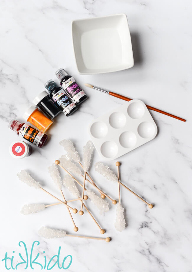 Materials for how to make rainbow rock candy on a white marble table.