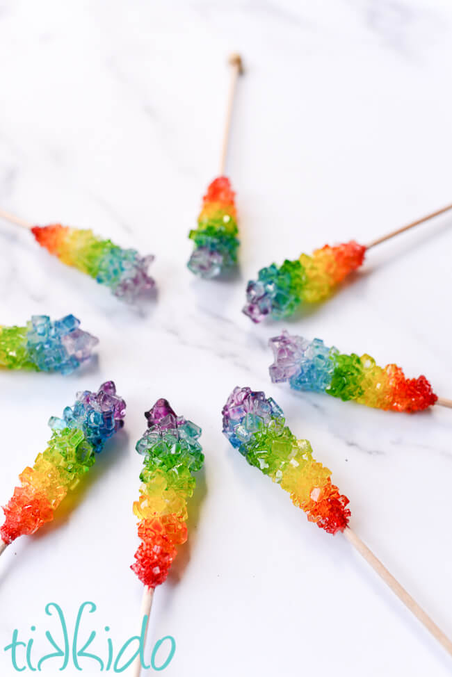 Eight sticks of rainbow rock candy arranged in a circle.