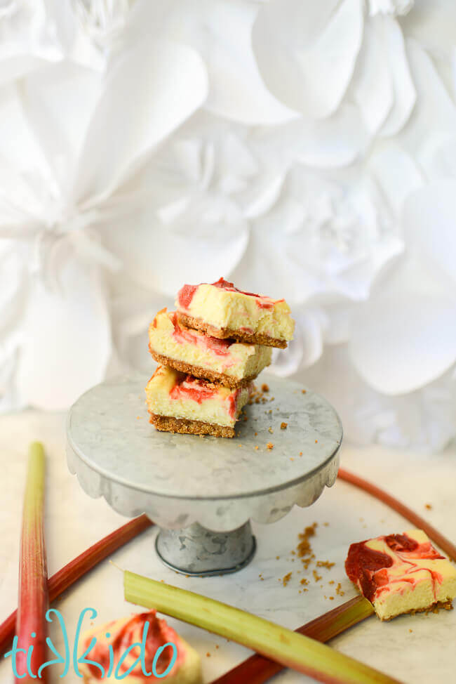 Rhubarb Cheesecake Bars stacked on a metal cake plate.