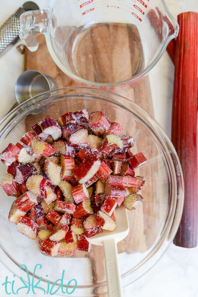 Rhubarb cobbler filling ingredients mixed together in a clear glass bowl.  