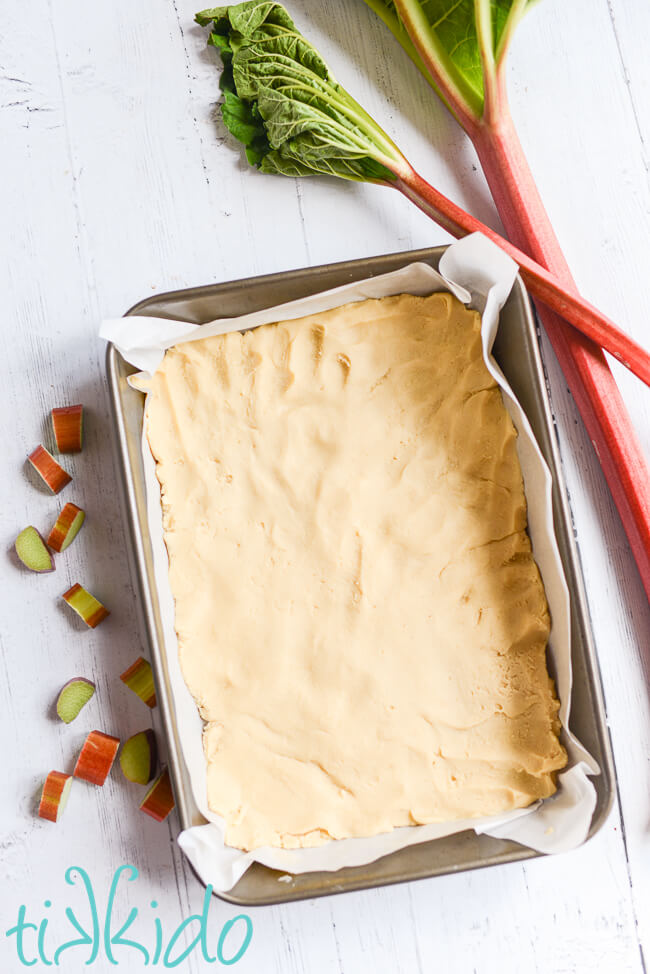 Shortbread crust for the Rhubarb Custard Bars Recipe pressed into a parchment paper lined 9x13 baking pan.